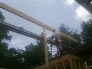Carpenter setting a ridge beam over a new addition frame — Ice Dam Removal by Roofing Brothers in Montauk