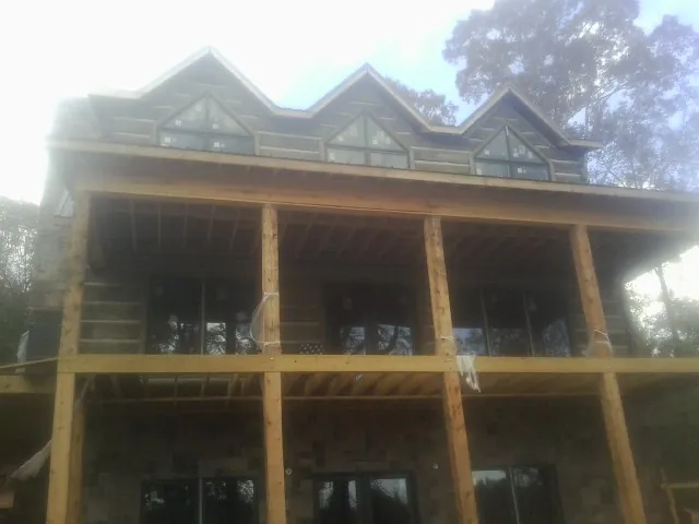 Dormers and porch framing on a large log home under construction — Roof Coating work by our crew in Montauk