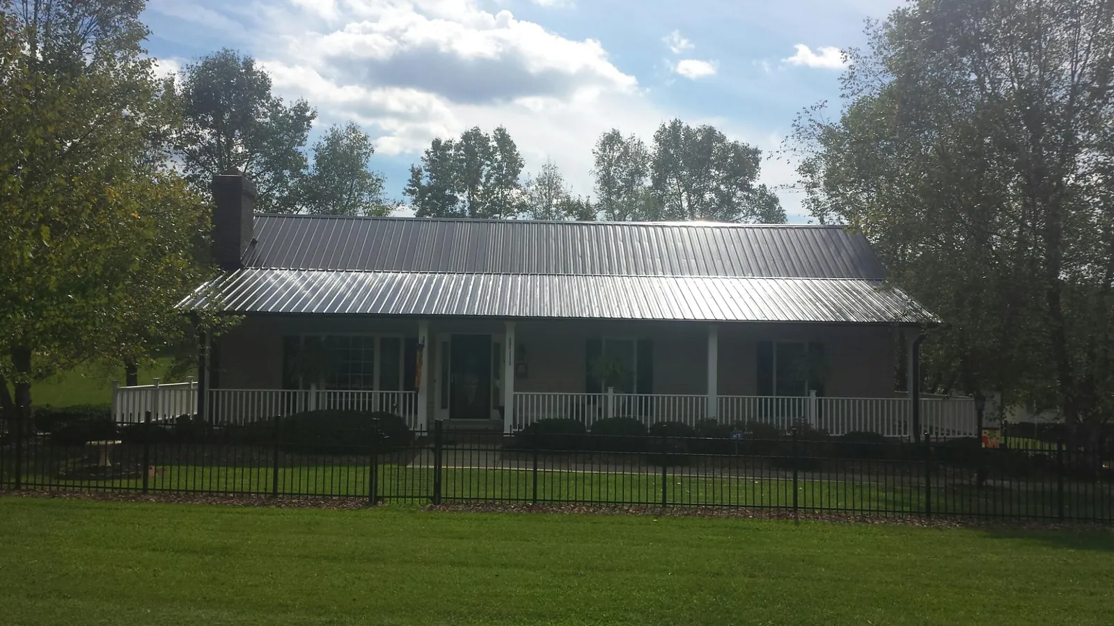 Gray metal roof on a brick ranch with a full width front porch — Gutter Guard Installation work by our crew in Montauk
