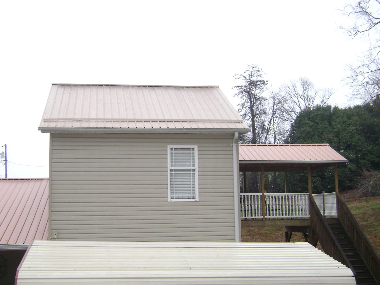 Tan metal roofs on a two story addition and attached porch, from a Roof Replacement job in Montauk