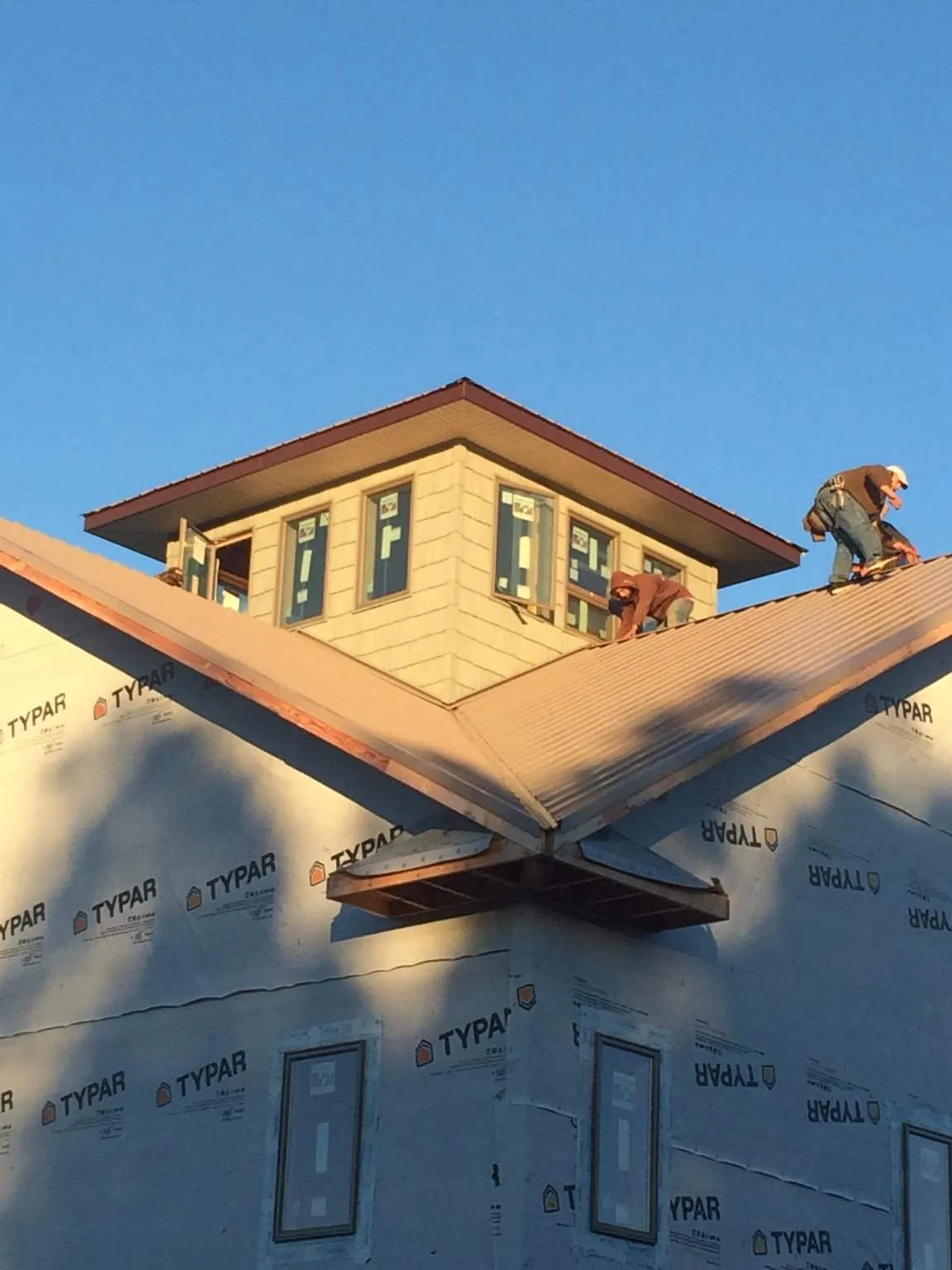 Roofers working around a rooftop cupola on a new metal roof at sunset — Roof Waterproofing in Montauk by Roofing Brothers
